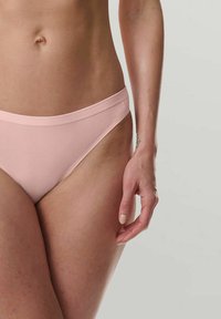 Lichtroze slipje met een naadloos ontwerp, zachte stof, matige bedekking en een smalle tailleband, met een gladde textuur.