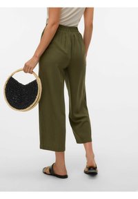 Pantalons cropped légers olive avec une taille élastique. Associés à un sac rond tissé noir et naturel et des sandales plates.