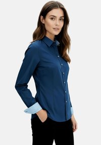 Navy blue button-up shirt with long sleeves, featuring striped light blue cuffs and a tailored fit. Smooth fabric texture, no patterns.