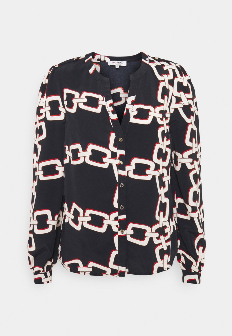 Blouse noire à manches longues avec motif chaîne blanche et rouge, boutonnée sur le devant, avec épaules légèrement bouffantes.