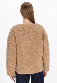 Brauner Fleece-Pullover mit einer strukturierten, flauschigen Oberfläche; verfügt über einen runden Hals und überschnittene Schultern. Weit geschnitten für einen bequemen Sitz, ideal zum Layering.