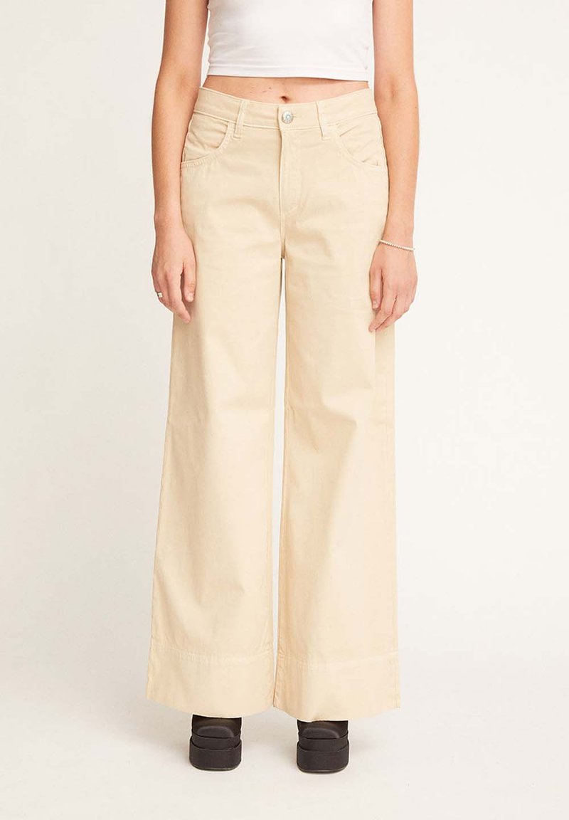 Pantaloni in cotone beige a gamba larga con vita media, dotati di tasche frontali e chiusura con bottone. Tessuto liscio e orlo rifinito.