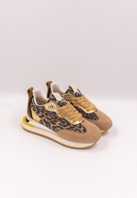 Ett par beige och bruna sneakers med leopardmönster, tjocka snören och vita sulor som har gula och svarta accenter.