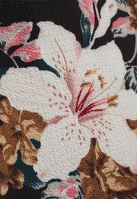 Primo piano di un motivo in tessuto floreale bianco e rosa con foglie verdi e accenti marroni su uno sfondo nero testurizzato.