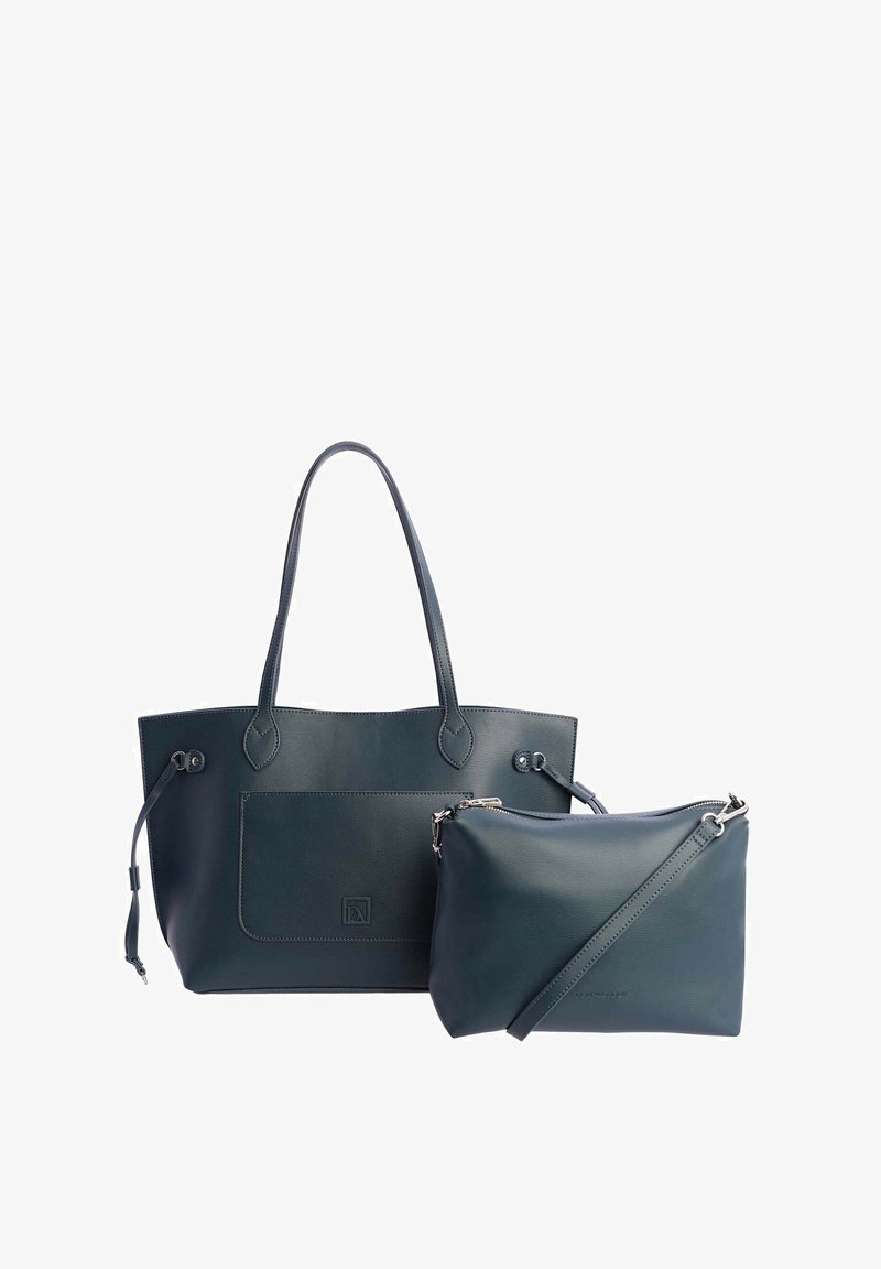 Gran bolsa tote de color azul oscuro con dos asas para el hombro y un bolsillo frontal, acompañada de un bolso cruzado más pequeño con cremallera y correa ajustable.