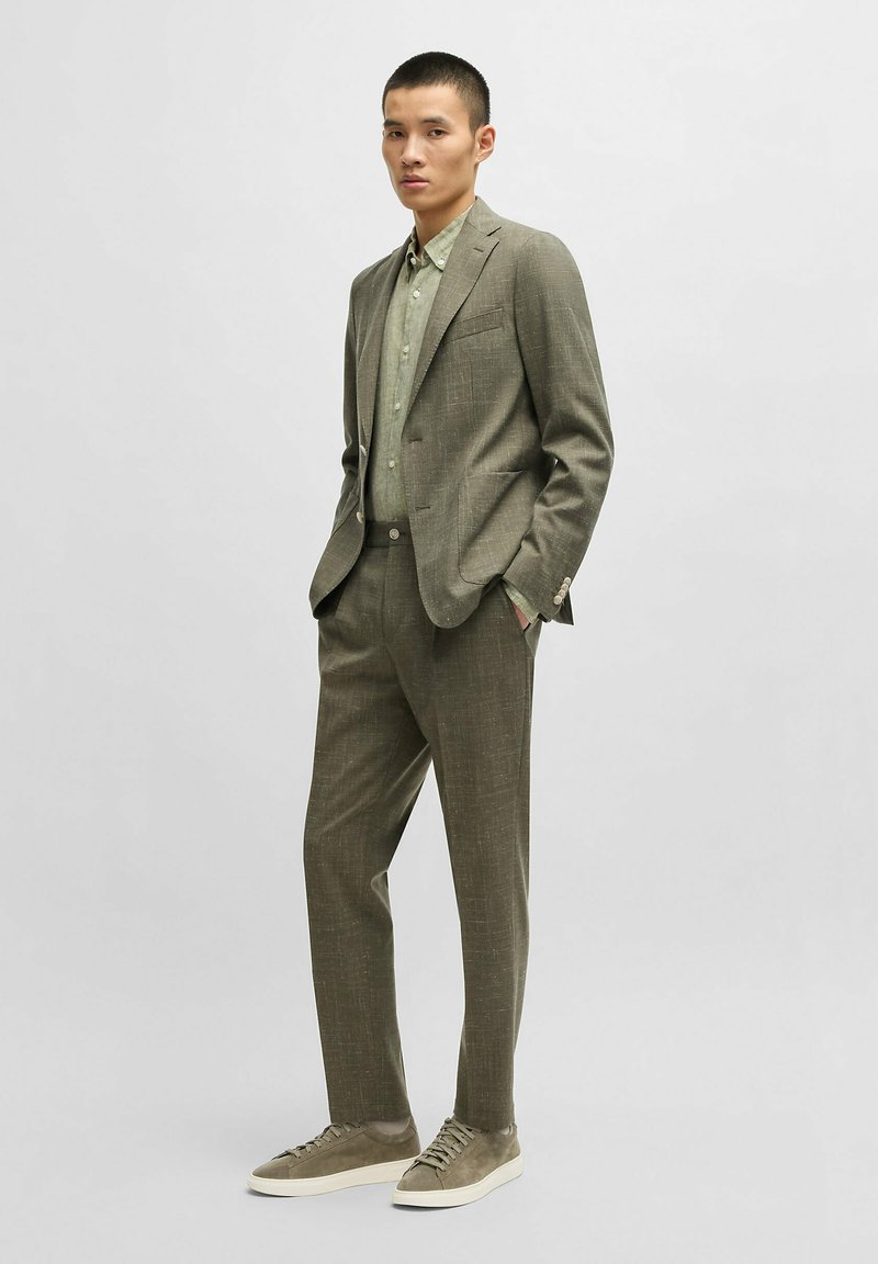 Light grey suit with subtle texture, paired with a pale green shirt. Complete look features grey sneakers. Tailored fit with pocket accents.
