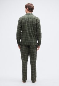 Conjunto de pijama a cuadros verdes que incluye una camisa de manga larga con botones y pantalones a juego, presentando un patrón de cuadrícula y un ajuste relajado.