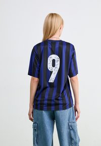Jersey deportivo a rayas negras y azules con un gran número 9 en blanco en la parte de atrás. Mangas cortas y diseño de cuello redondo. Corte casual.