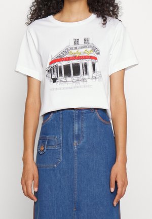 T-shirt blanc avec une esquisse d’une devanture de café indiquant "Seeby Café SEEBYCHLOE,", associé à une jupe en jean bleue taille haute.