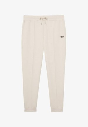 Pantalones jogger beige con cintura elástica con cordón, tobillos con puños, bolsillos delanteros y un pequeño parche rectangular en el muslo derecho.