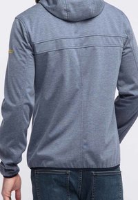 Grå huva jacka med en slät textur, med en skräddarsydd passform och sömdetaljer över ryggen. Kombination med blå denimjeans.