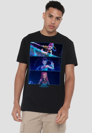 Young man wearing black t-shirt with three animated female characters from K-Pop Demon Hunters in vibrant blue and purple tones.