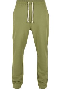 Olijfgroene sweatpants van zachte stof, met een elastische tailleband met trekkoorden en taps toelopende pijpen met zijzakken.