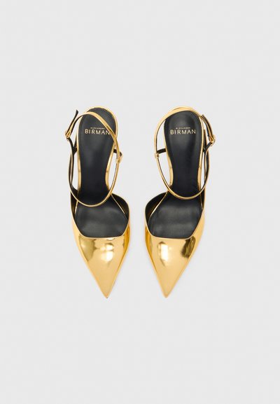 Escarpins slingback en cuir verni doré avec des orteils pointus, doublure intérieure noire et une fine lanière à la cheville. Fini lisse et brillant.