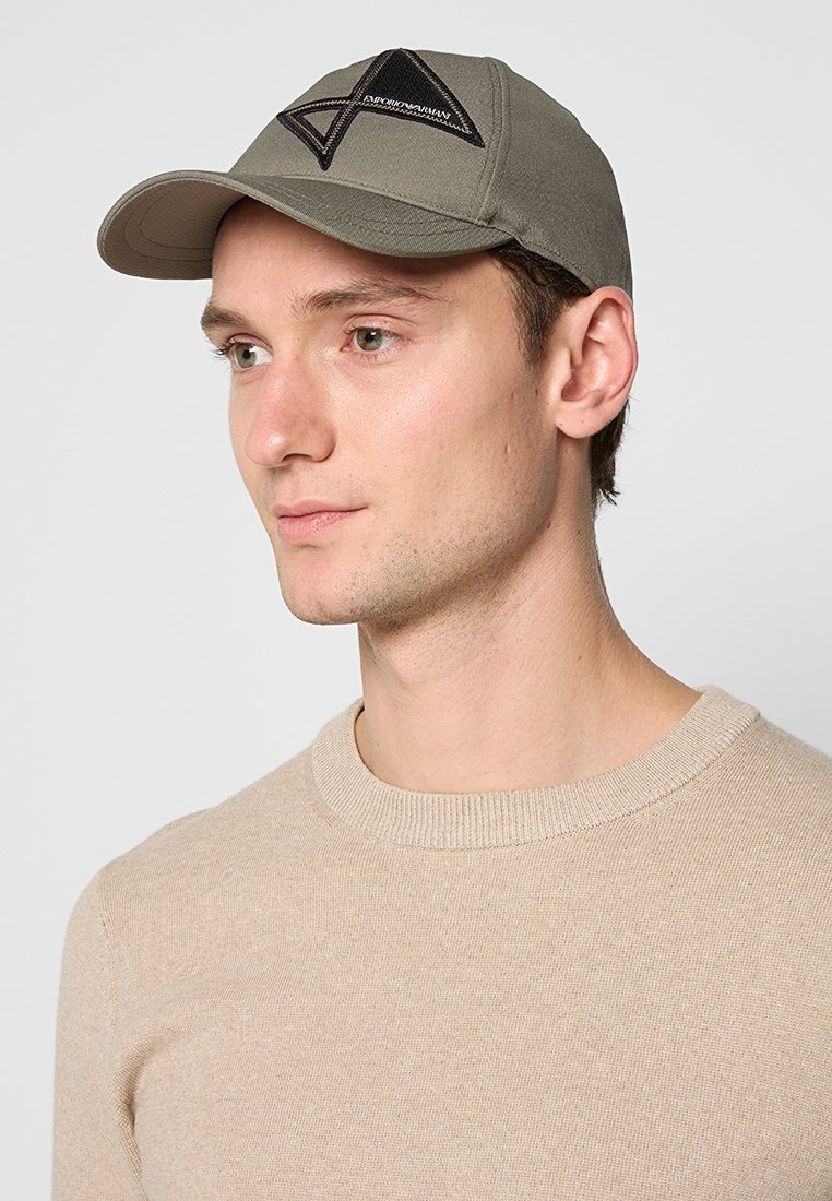Gorra de béisbol khaki de algodón, con parche triangular negro y logotipo bordado en la parte delantera, con visera curvada y diseño estructurado.