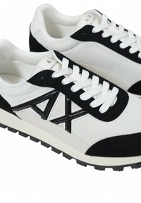 Baskets de sport noir et blanc avec un dessus en maille, des accents en daim, un logo en relief et une semelle en caoutchouc texturée.