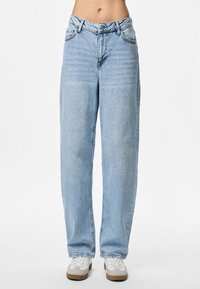 Calças de ganga azul claro com cintura alta, pernas direitas largas, design de cinco bolsos e fecho de correr. Combinadas com ténis brancos.