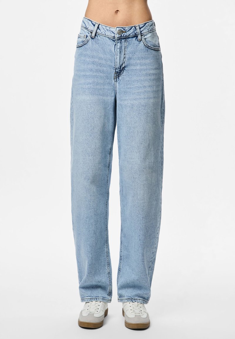 Calças de ganga azul claro com cintura alta, pernas direitas largas, design de cinco bolsos e fecho de correr. Combinadas com ténis brancos.