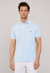 Polo bleu clair avec un col classique, des manches courtes et un petit logo brodé sur la poitrine. Fabriqué en tissu de coton lisse.
