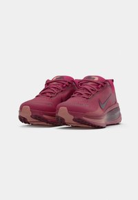 Nike bėgimo bateliai tamsiai rožinės spalvos su tekstūruotu tinkliniu paviršiumi, su raišteliais ir guma padu, kuriame yra sukibimo raštai.