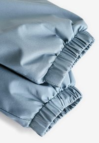 Tissu bleu clair avec une texture lisse, comportant des poignets élastiques et une finition légèrement brillante.