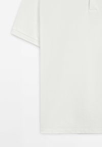 Bílá polo košile s krátkým rukávem vyrobená z texturované bavlny, s jemným límcem a jednou náprsní kapsou. Jednoduchý, celistvý design.