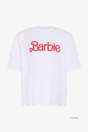 Λευκό T-shirt με κοντά μανίκια και κόκκινο κείμενο "Barbie" στο κέντρο μπροστά, σε χαριτωμένη, καλλιγραφική γραμματοσειρά.