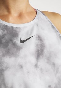 Canotta atletica grigia realizzata in tessuto leggero, con scollatura arrotondata, delicate fantasie a nuvola e logo Nike nero sul petto.