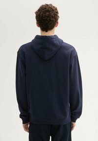 Námornícky modrá mikina s kapucňou na šnúrku, voľného strihu, s rebrovanými manžetami a dole, s jemnou textúrou a minimalistickým dizajnom.