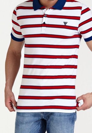 Homme portant un polo à manches courtes blanc avec des rayures horizontales rouges et bleu marine et un col bleu marine, associé à un jean bleu.