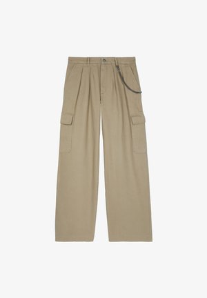 Pantalones cargo de pierna ancha beige con pliegues delanteros, bolsillos con solapa en los lados, presillas para cinturón, cierre con botón y cadena metálica adjunta en el lado derecho.