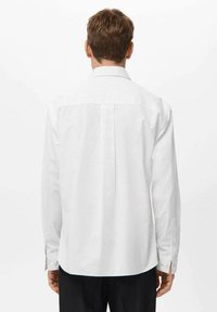 Camisa blanca de manga larga con rayas verticales en gris claro, con cuello doblado y puños abotonados. El material parece suave con un ajuste entallado.