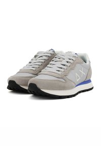 Zapatillas de ante y malla grises con una suela blanca, con un acento azul en el talón y una suela de goma negra, y un diseño de cordones.