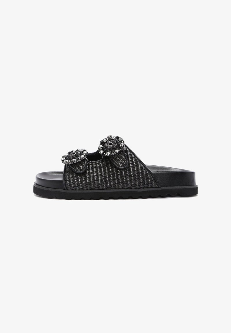 Black slide sandals featuring a woven texture, two decorative buckles with rhinestones, and a thick, ridged rubber sole.