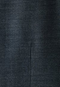 Tummansininen denimpuku, jossa on teksturoitu kudos. Sisältää hienovaraisen kiiltävän pinnan ja näkyvät saumat, joissa on lievä uurre. Yksi pystysauma on läsnä.