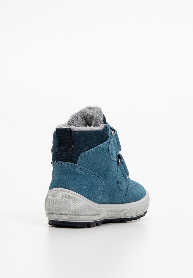 Blaue Wildleder-Stiefelette mit grauem Kunstfellfutter, Klettverschlüssen, weißer Gummisohle und strukturierten Details an der Ferse und an der Seite.