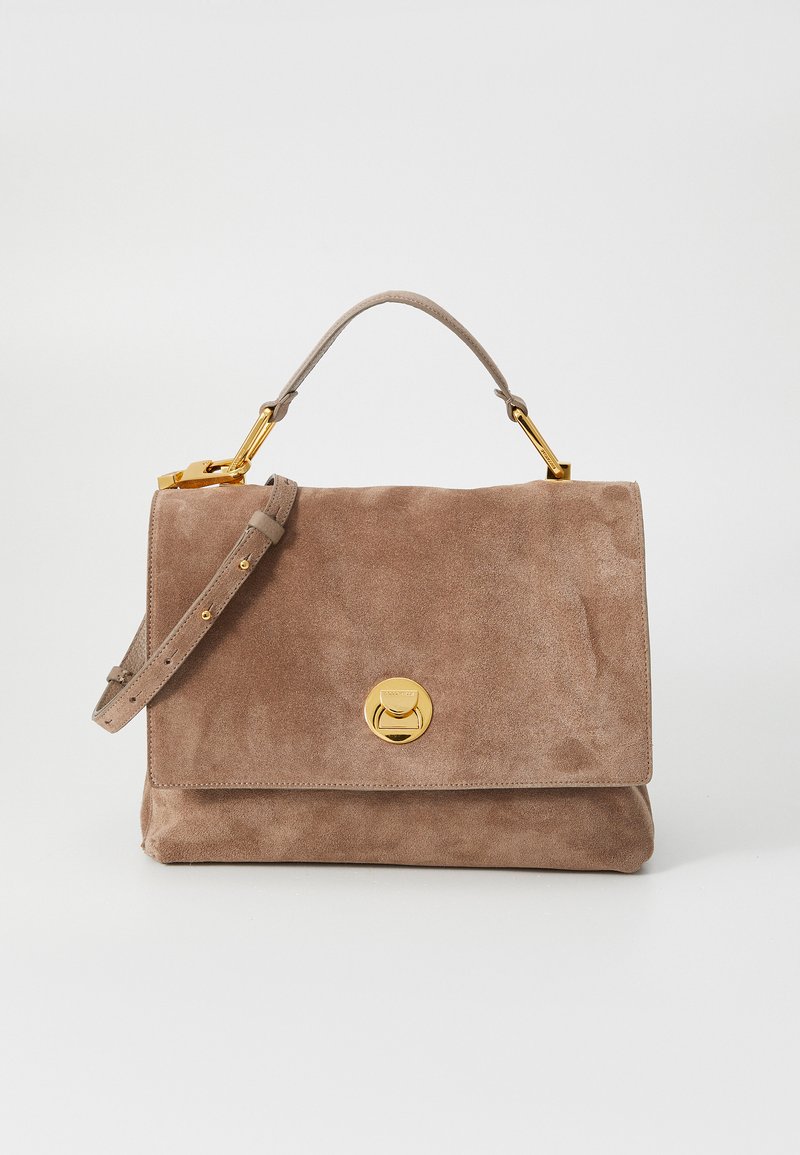 Bolsa de mão em camurça castanha com um formato estruturado. Apresenta uma alça de mão, uma alça destacável e um detalhe de fecho circular em tom dourado.
