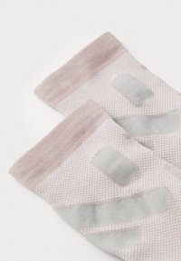 Calcetines deportivos de un rosa claro con un tejido texturizado y detalles en gris, con puños acanalados y áreas de ventilación para mayor transpirabilidad.