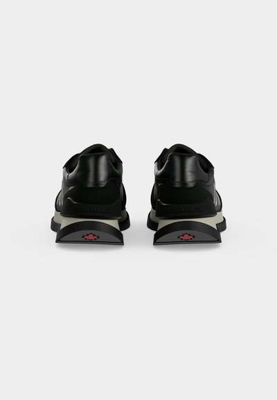Paire de baskets noires avec semelles intermédiaires blanches vues de dos sur fond blanc, avec des logos de feuille d'érable rouges sur les talons.
