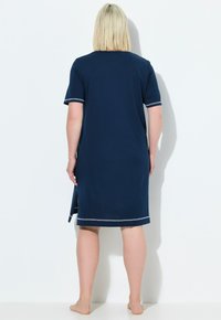 Granatowa bawełniana nocna koszula z krótkimi rękawami, bocznymi rozporkami oraz jasnoszarym wykończeniem przy rękawach i u dołu. Gładka tekstura, długość do kolan.