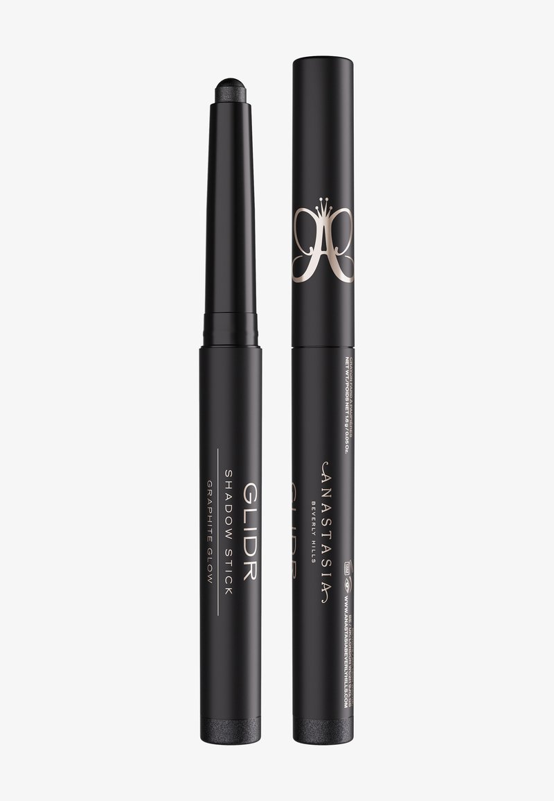 Deux crayons à fard à paupières cylindriques noirs, l'un avec le capuchon enlevé montrant une pointe foncée et scintillante, étiqueté "Anastasia Beverly Hills Glidr Shadow Stick".
