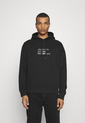 Felpa in cotone nera con tasca a marsupio frontale, cappuccio con lacci e testo stampato in bianco che recita "CALVIN KLEIN EST. 1968 NEW YORK CITY."
