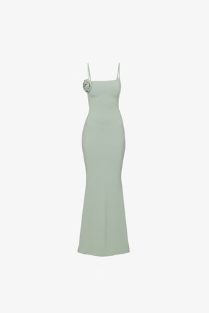 Vestido verde claro, hasta el suelo, sin mangas, con tirantes finos y un detalle de flor en el hombro izquierdo.