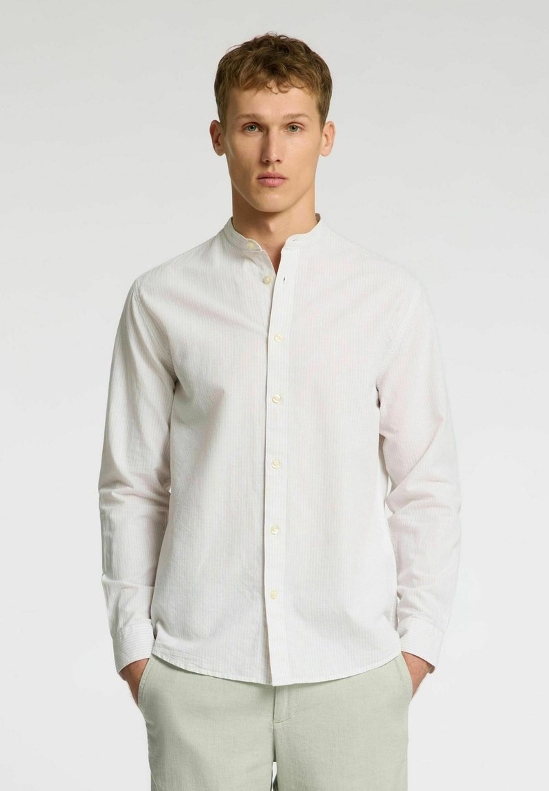 Camisa blanca de manga larga y con botones, con cuello mao, que presenta finas rayas verticales. La tela parece suave con un ligero brillo.