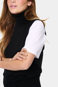 Must kürtsega musta turtleneck-top, millel on valge lühikeste varrukatega särk aluses. Topil on sooniline tekstuur ja kindel istuvus, pehme viimistlusega.