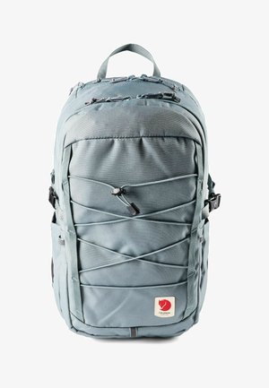 Lichtgrijze rugzak met elastische koorden aan de voorkant, meerdere ritssluitingsvakken, zijgespen, bovenhandvat en een rood voslogo op een applicatie onderaan.