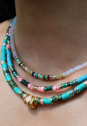 Collier à perles multi-couches en turquoise, rose et vert, avec des accents dorés. Comprend différentes formes de perles et éléments décoratifs.