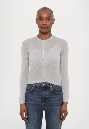Lys grå, langermet cardigan i en gjennomsiktig, strikket tekstur med knapper foran. Kombinert med mørk denimbukse.