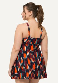 Robe colorée avec un motif abstrait audacieux en marine, orange et teal. Le design comprend des bretelles réglables et un ourlet évasé.