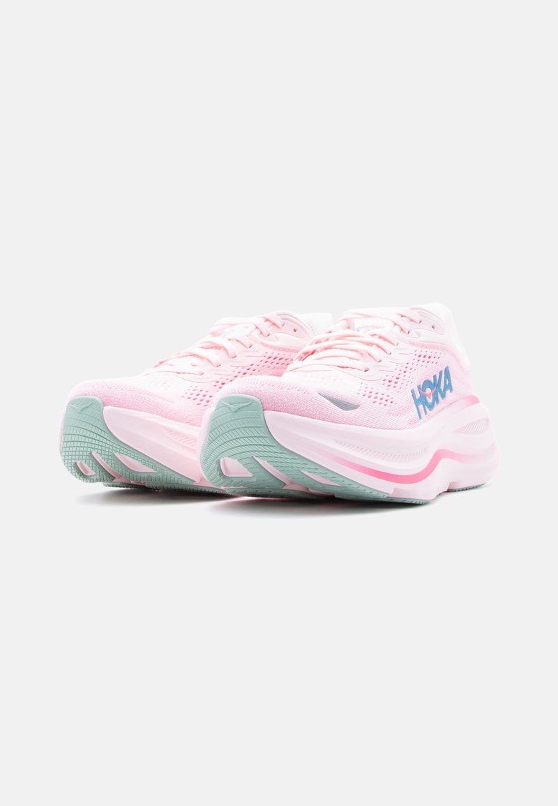 Paire de chaussures de course Hoka rose clair avec logo bleu et semelles en caoutchouc vert clair, vues de l'angle avant gauche sur fond blanc.